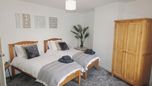 Een slaapkamer met twee bedden, een kledingkast en een plant in pot.