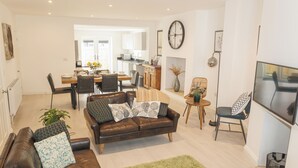 Een moderne woonkamer met een bruine leren bank, een groen vloerkleed en een televisie.