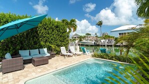 A pool area with lounge chairs, a covered seating area, and a view of the marina. - Flamingo Bay~ Pool, Cabana Club, 30' Dock! (Key Colony Beach)
