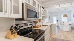 A modern kitchen with white cabinetry, stainless steel appliances, and a central island with a sink. - Flamingo Bay~ Pool, Cabana Club, 30' Dock! (Key Colony Beach)