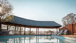 Ett poolområde med en överbyggd sittplats och solstolar.