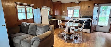 Cocina compacta con refrigerador, estufa y comedor con sillas y mesa.