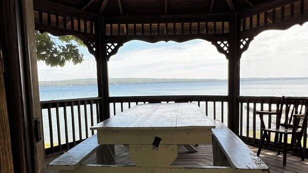 Un pabellón de madera con mesa de picnic, con vista a un cuerpo de agua.