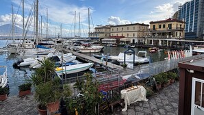 A marina with various boats docked, a stone-paved walkway, and buildings in the background. - A un passo dal cuore di Napoli: Rosso Napoli Short Lets (Napoli)