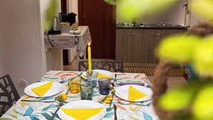 A dining table set with yellow napkins, plates, and glasses, a candle, and a small vase with flowers. - A un passo dal cuore di Napoli: Rosso Napoli Short Lets (Napoli)