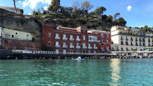 A waterfront view with a row of buildings, including a prominent red building with multiple balconies. - A un passo dal cuore di Napoli: Rosso Napoli Short Lets (Napoli)
