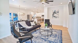 Un salon moderne avec un canapé, des fauteuils, une table basse et un ventilateur de plafond.