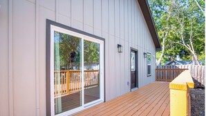 Un bâtiment moderne doté d’une terrasse en bois, de grandes portes-fenêtres coulissantes et d’une cour arrière clôturée.