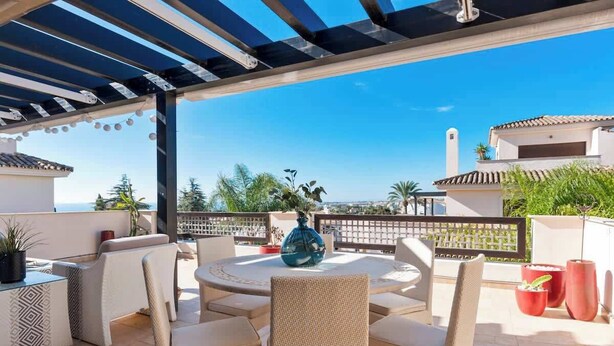 An outdoor patio with a round table and chairs, surrounded by potted plants and a pergola. - Apt with pool Marbella by Costarentals - Ref M51 (Marbella)