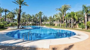 A circular swimming pool surrounded by palm trees and greenery, with a clear blue sky above. - Apt with pool Marbella by Costarentals - Ref M51 (Marbella)