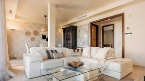 A modern living room with a white sectional sofa, a glass coffee table, and a large mirror. - Apt with pool Marbella by Costarentals - Ref M51 (Marbella)