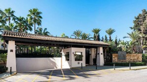 A hotel entrance with a covered walkway, palm trees, and a clear sky. - Apt with pool Marbella by Costarentals - Ref M51 (Marbella)