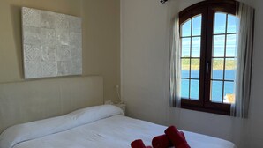 Une chambre à coucher avec un lit, une fenêtre donnant sur la mer et un élément décoratif mural.