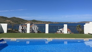 Une piscine avec vue sur la mer et les collines.