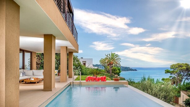 A modern pool area with a clear view of the sea, surrounded by greenery and a white building with a balcony. - Villa Mulberry 10, Emma Villas (Sciacca)