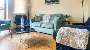 Un salon avec un canapé bleu, une table basse ronde et un fauteuil bleu.