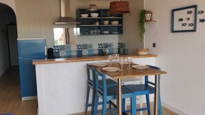 A kitchen with a blue refrigerator, a wooden island with two blue chairs, and a tiled backsplash. - Dream rental, balcony with magnificent pool view (Empuriabrava)