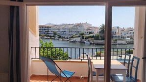 A balcony with a view of a waterfront, a table, and two chairs. - Dream rental, balcony with magnificent pool view (Empuriabrava)