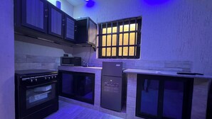 Cocina compacta con estufa, microondas, refrigerador y armarios.