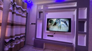 Una sala de estar moderna con un televisor de pantalla plana montado en la pared, una cortina estampada y piso de madera.