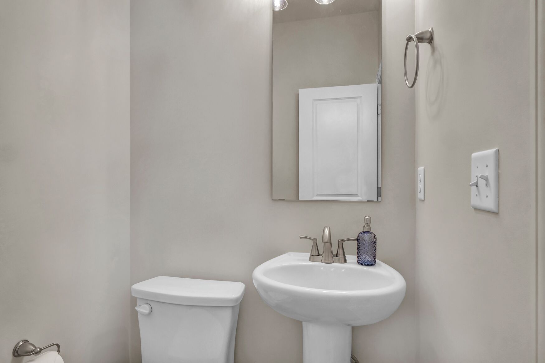 A bathroom with a toilet, sink, and mirror.