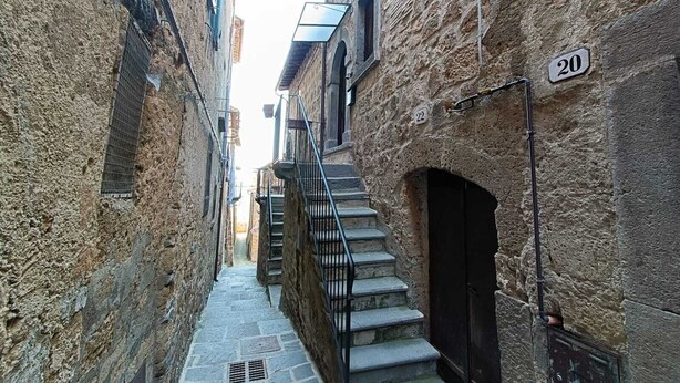 Ein schmaler, mit Kopfsteinpflaster belegter Gang mit einer Treppe, die zu einem Gebäude führt.