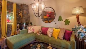 A cozy living room with a green sofa, a fireplace, a chandelier, and Christmas decorations.