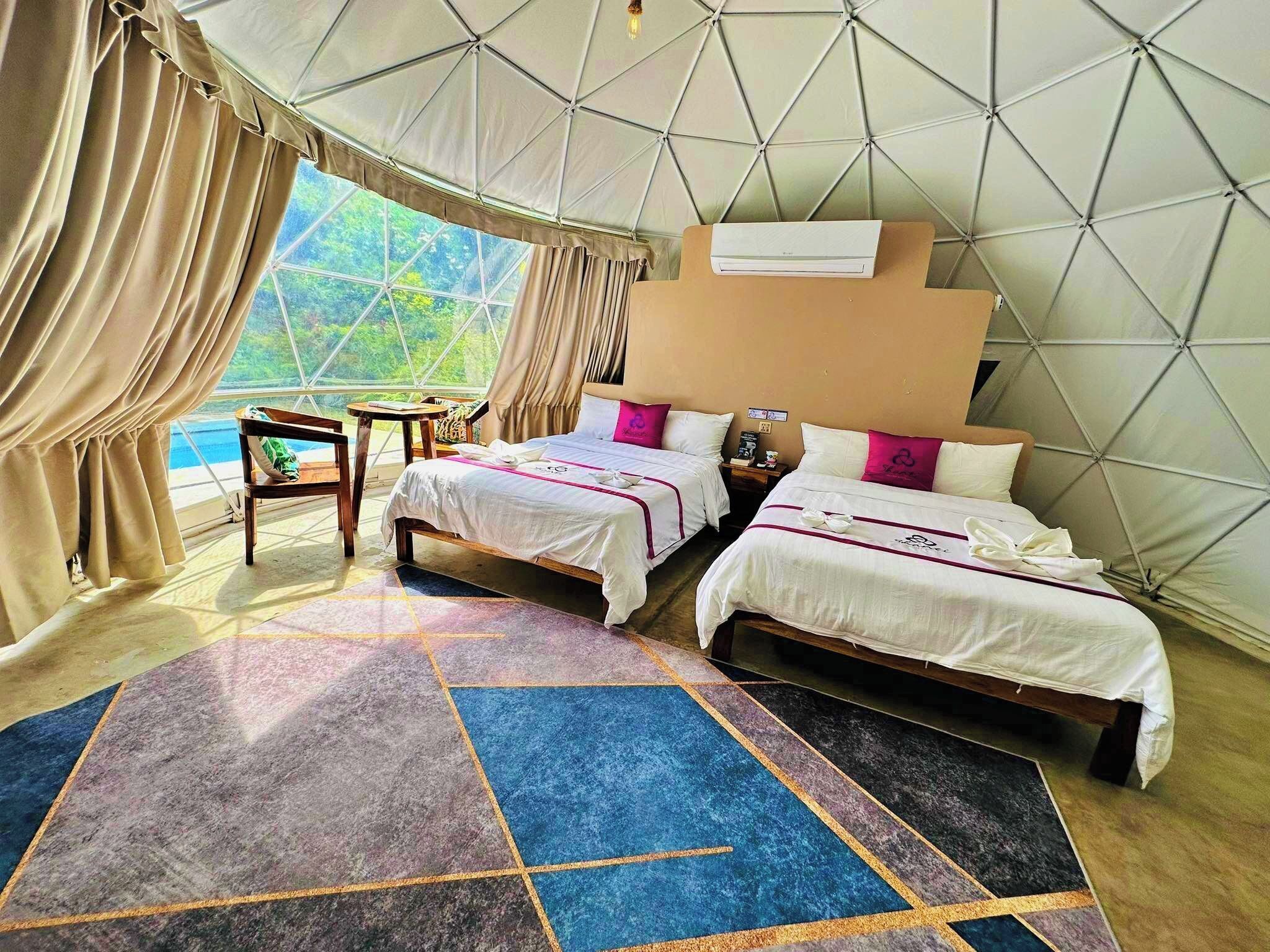A room with two beds, a small table, and a window with curtains.