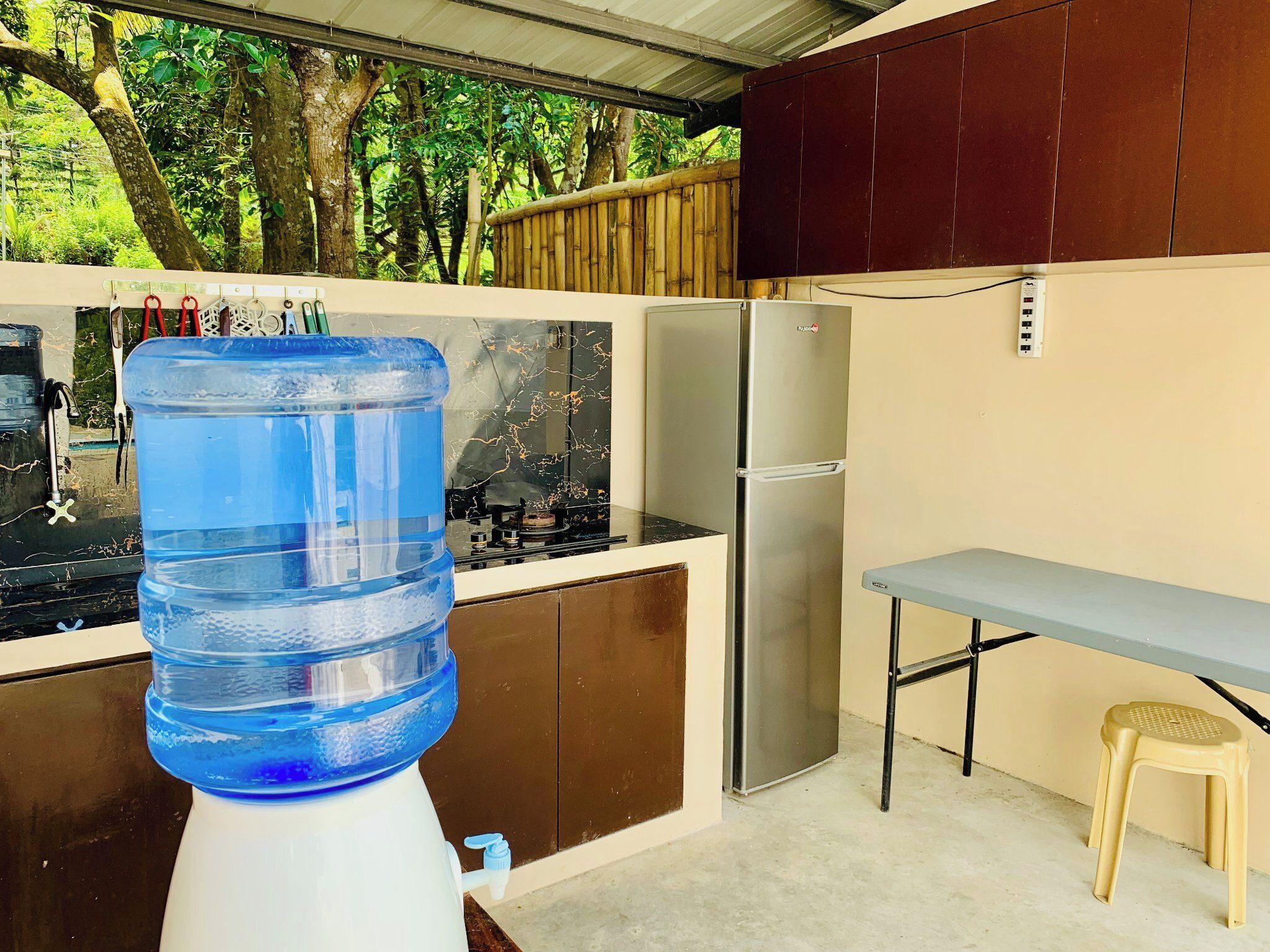 A compact kitchen with a water dispenser, a refrigerator, and a gas stove.