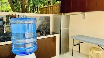 A compact kitchen with a water dispenser, a refrigerator, and a gas stove.