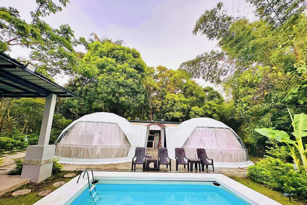 Un espace piscine doté de deux structures abritées et d’une table avec des chaises.