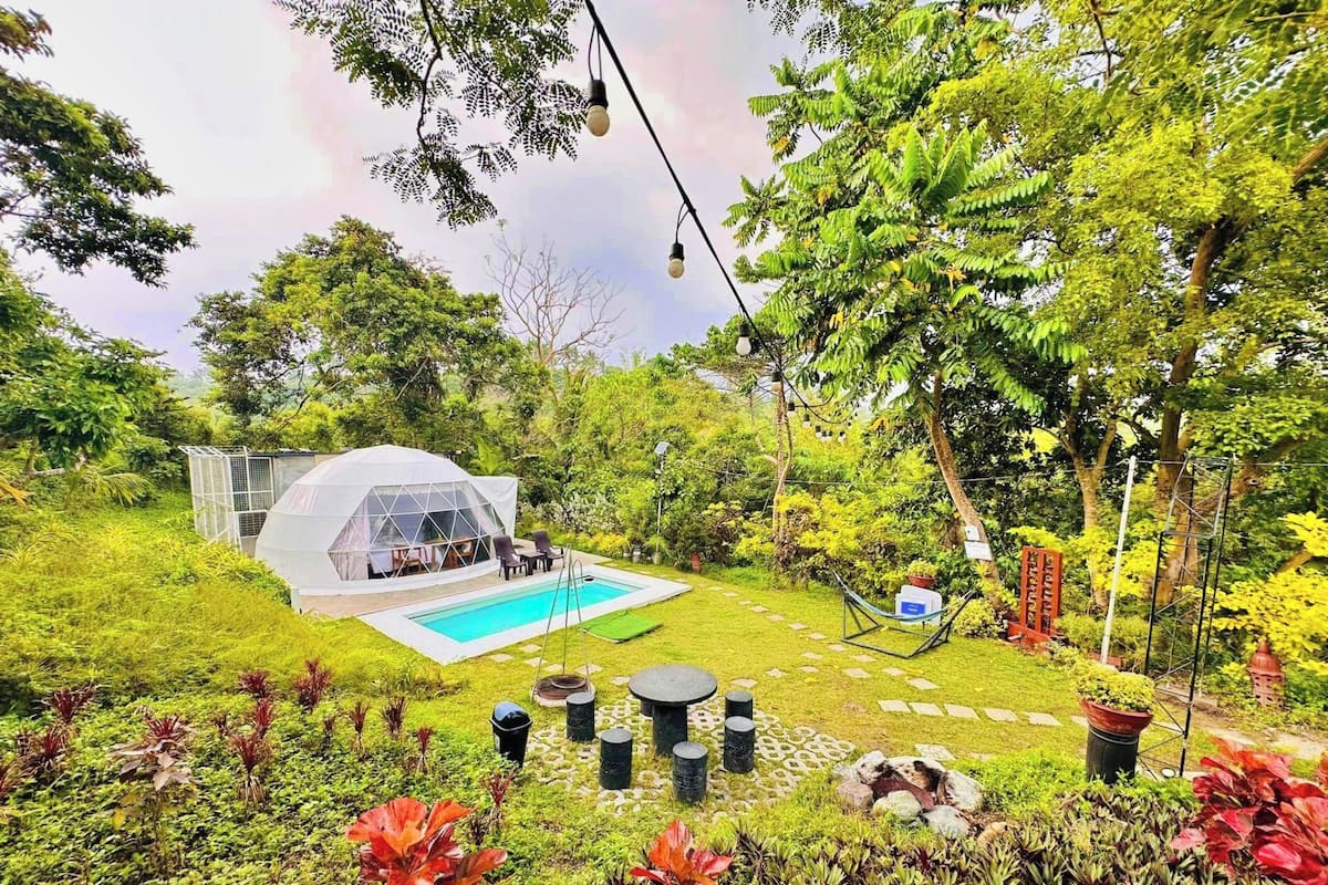 Un jardin privé avec une piscine, un kiosque et diverses plantes.