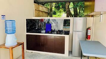 A compact kitchen with a water dispenser, a refrigerator, and a small table.