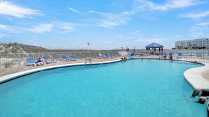 En swimmingpool med blå solstolar och en lusthus.