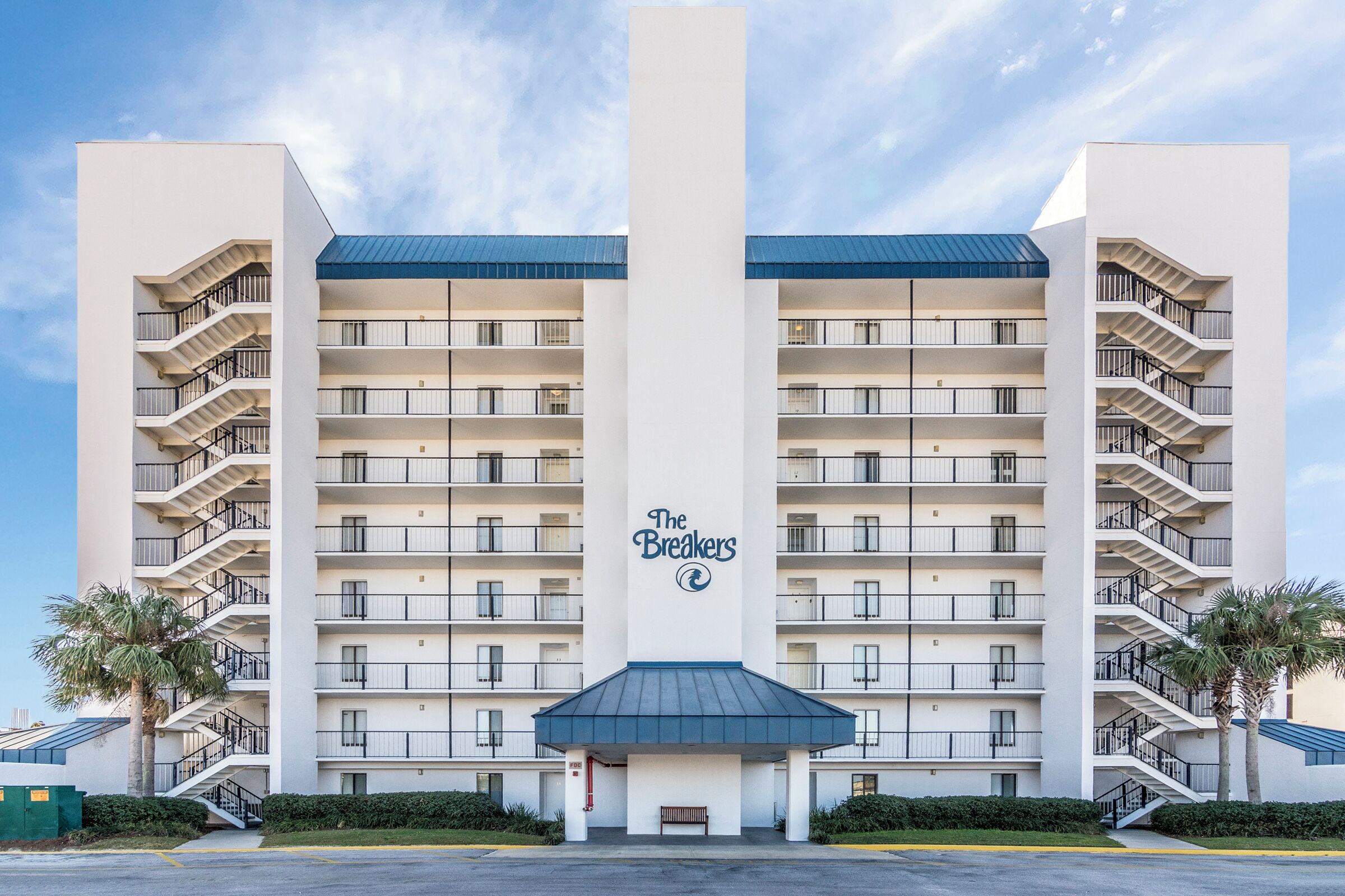 A multi-story hotel with a central entrance, balconies on each floor, and a sign reading "The Breakers".