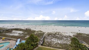 Ett semesterhotell vid stranden med en pool, en livräddartorn och en strandpromenad som leder ner till stranden.