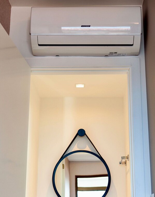 Un appareil de climatisation blanc est fixé au-dessus d’une porte, et un objet circulaire est suspendu au mur en dessous.