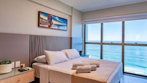 A modern hotel room with a large bed, a view of the sea, and a painting on the wall. - 2 Bedrooms with Home Office Sea View in Barra (Salvador)