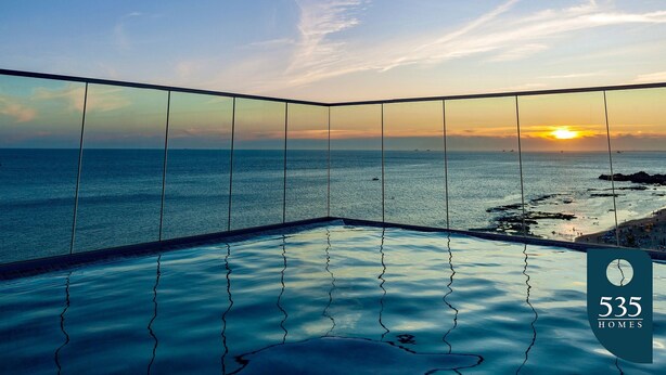 An infinity pool with a view of the ocean and sunset.