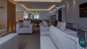 Een moderne hotellobby met witte banken, een eetgedeelte en een keuken.