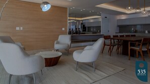 Een moderne woonkamer met een bank, fauteuils, een salontafel en een eethoek met een houten tafel en stoelen.