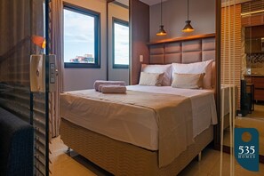 A hotel room with a large bed, a window, and a view of the city.