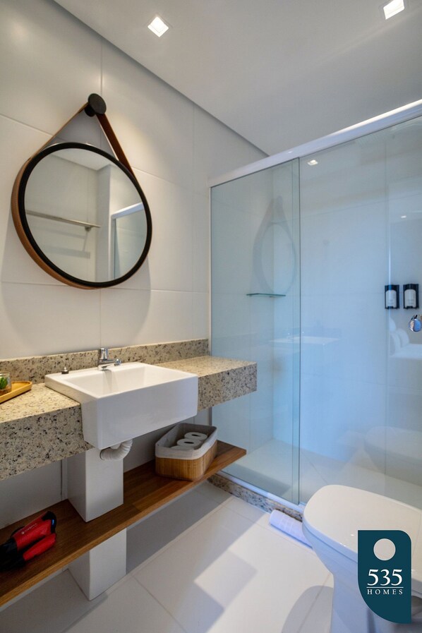A modern bathroom with a freestanding sink, a glass shower enclosure, and a toilet.