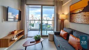 Una sala de estar moderna con un sofá, una mesa de centro, un televisor y un balcón con vista a la ciudad.