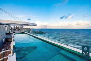 A swimming pool with a view of the ocean and a city skyline. - Experience the Charm of Barra Near the Lighthouse (Salvador)