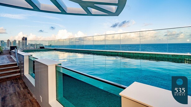 A rooftop infinity pool with a city skyline and ocean view. - Experience the Charm of Barra Near the Lighthouse (Salvador)