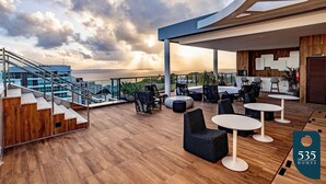A rooftop terrace with wooden flooring, outdoor seating, and a staircase leading to an upper level. - Experience the Charm of Barra Near the Lighthouse (Salvador)