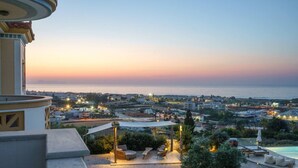 Une terrasse sur le toit offrant une vue sur la ville et la mer au crépuscule.