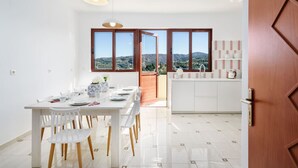 Une cuisine moderne avec des meubles blancs et une vue sur la campagne, grâce à de grandes fenêtres.