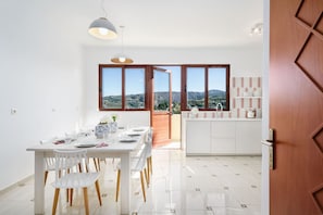 Een moderne keuken met witte kasten en uitzicht op het platteland door grote ramen.